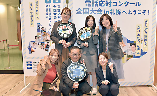 コンクール全国大会パネル前で写真撮影